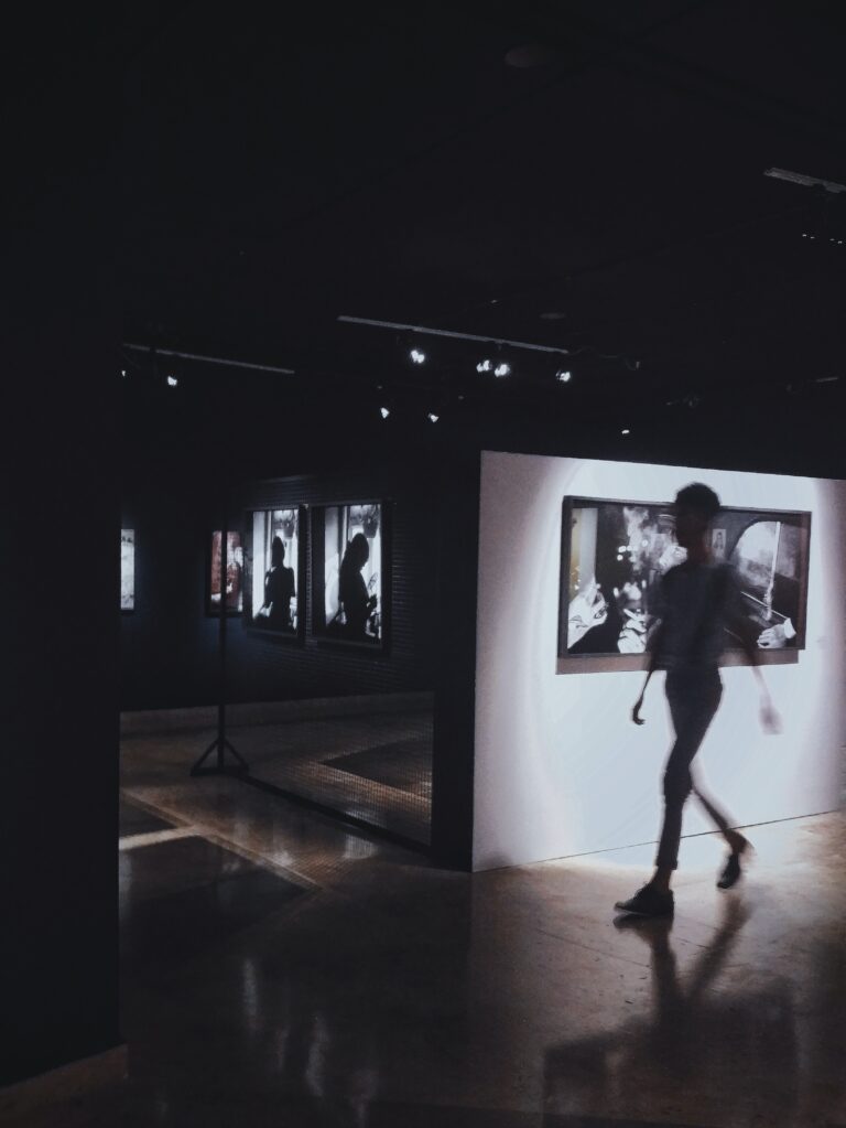Woman walking through art gallery. photo by Matheus Viana. Courtesy of Pexels