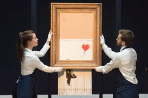 Sotheby's staff members present Banksy's "Love is in the Bin" in London, Britain on Oct. 12, 2018. Originally titled "Girl with Balloon", Credit: Ray Tang/Xinhua/Alamy Live News