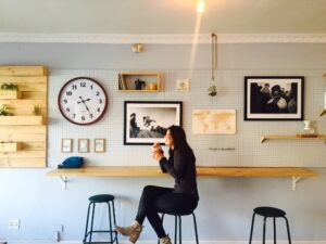 Woman sitting next to her gallery wall. Courtesy of Unsplash 